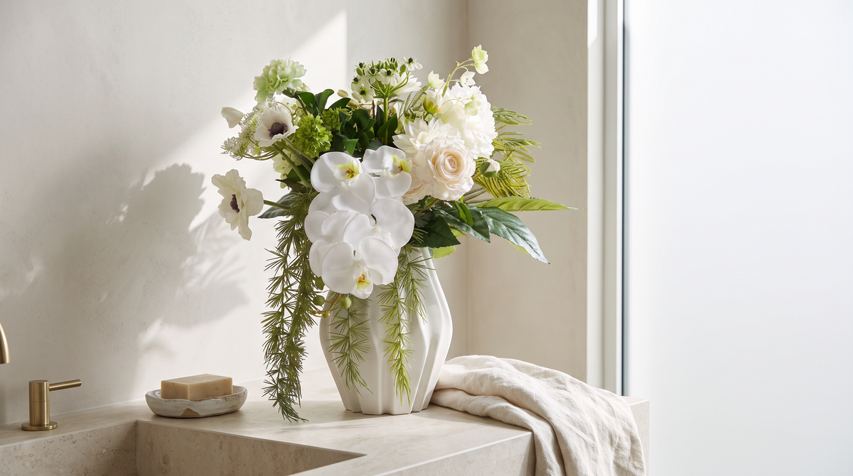 Kunstbloemen in de badkamer: kunstboeket Linda met witte orchideeën in een witte vaas op een stenen wastafelblad