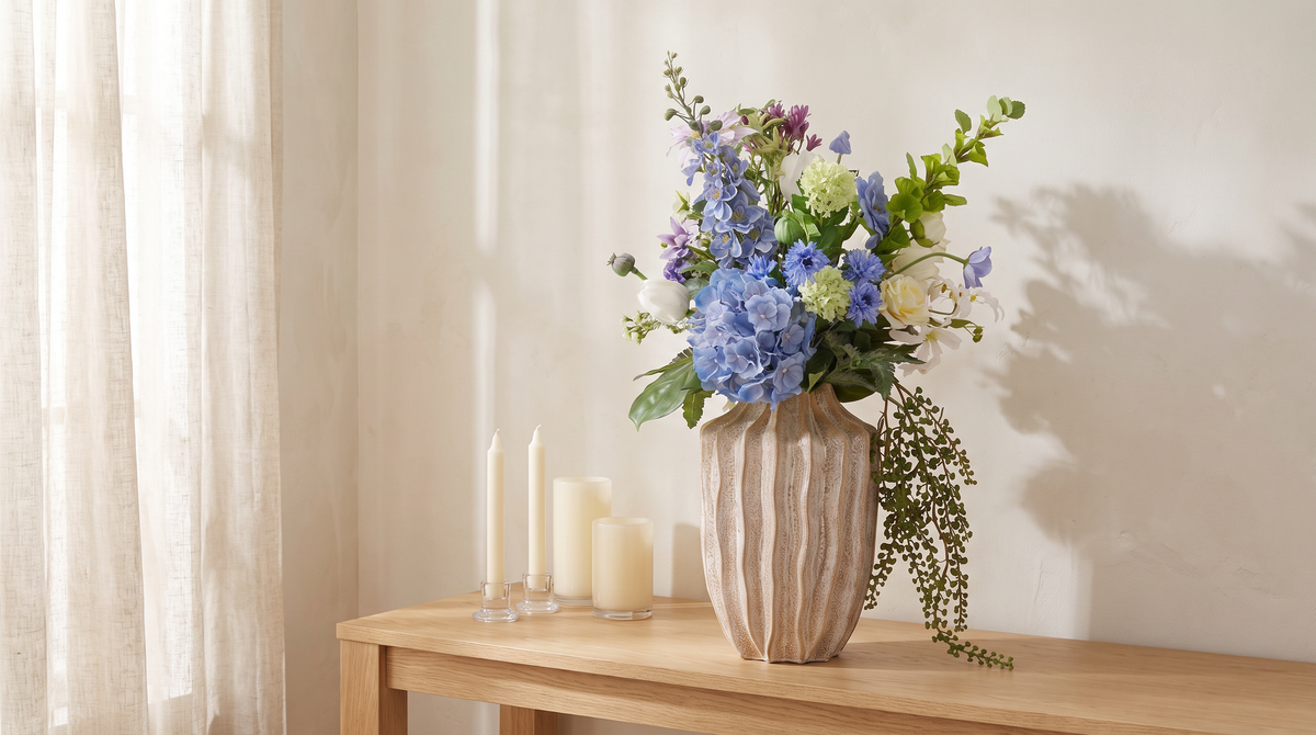 Wit-blauw kunstboeket Riga met pioenrozen en hortensia op een eiken sidetable, sfeerbeeld voor een bruidsboeket van zijden bloemen